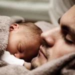 Father holding his newborn son with message that babies are born perfect and circumcision is unnecessary